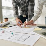 Close-up image of architects working on building blueprint